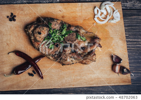 cooked pork meat on a wooden chopping Board with spices 48702063