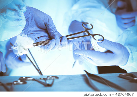 Surgeons hands holding surgical scissors and passing surgical equipment, close-up. Health care and Surgeons hands holding surgical scissors and passing surgical equipment, close-up. Health care and 48704067