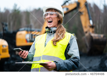Worker woman in open-cast mining using phone 48704486