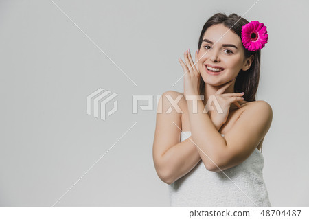 Beautiful young girl standing on a white background. During this time there is a flower in the hair 48704487