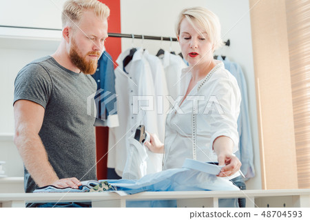 Tailor and customer looking at pattern book choosing materials Tailor and customer looking at pattern book choosing materials 48704593