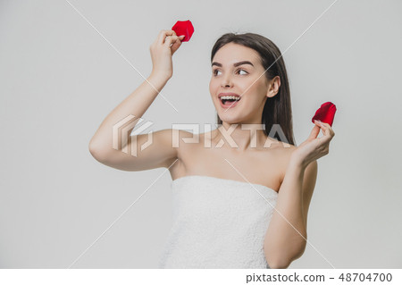 Young pretty girl standing on a white background. During this, he raised his hands with red petals Young pretty girl standing on a white background. During this, he raised his hands with red petals 48704700