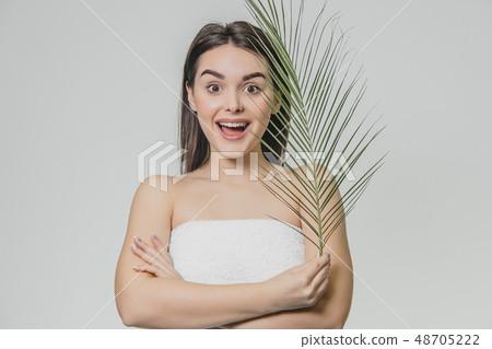 The face is a beautiful young woman with clean, perfect skin, covered with leaves. Portrait of a 48705222