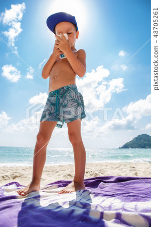 Cute boy is playing in a  mobile phone on the beach  48705261
