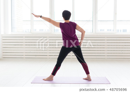 Sport, yoga, people concept - Sporty middle-aged woman practicing yoga indoors Sport, yoga, people concept - Sporty middle-aged woman practicing yoga indoors 48705696