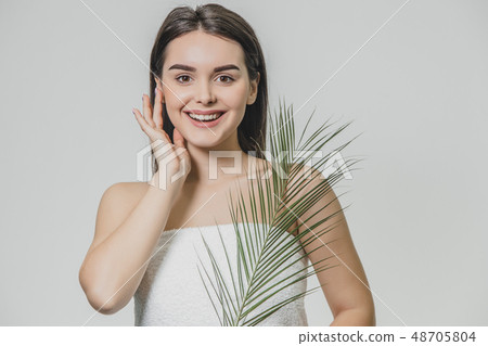 A beautiful young girl in the studio on a white background with wet skin and wet hair holds a large A beautiful young girl in the studio on a white background with wet skin and wet hair holds a large 48705804