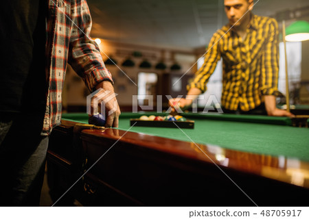 Two male billiard players places colorful balls 48705917