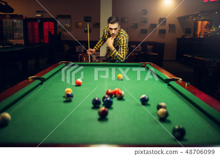 Male billiard player with cue thinking how to hit Male billiard player with cue thinking how to hit 48706099
