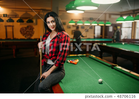 Female billiard player with cue poses at the table 48706116