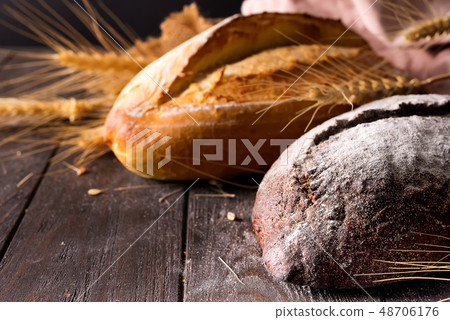 Rustic bread roll or french baguette, wheat and flour on wooden. Rural kitchen or bakery - 48706176