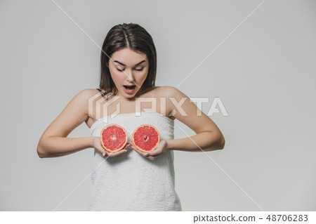 Happy young girl posing with fruit. Slices of red grapefruit in her hands on a white background Happy young girl posing with fruit. Slices of red grapefruit in her hands on a white background 48706283