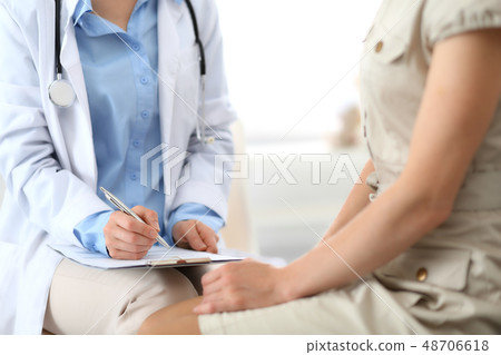 Doctor and patient talking. Physician at work in hospital while writing up medication history Doctor and patient talking. Physician at work in hospital while writing up medication history 48706618