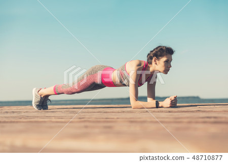 Sporty young girl in the morning on the pier on seashore, practicing yoga. Woman do gymnastics Sporty young girl in the morning on the pier on seashore, practicing yoga. Woman do gymnastics 48710877