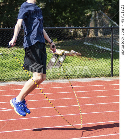 Runner jumping rope on a track 48711223