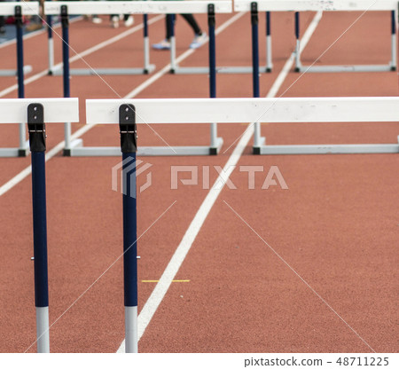 Hurdles on a red indoor track 48711225