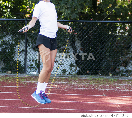 Runner jumping rope on a track 48711232