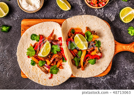 FAJITAS with colored pepper and onions, served FAJITAS with colored pepper and onions, served 48713063