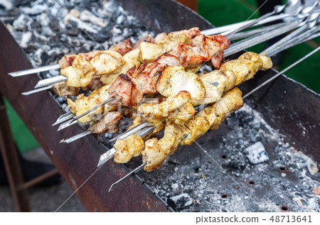 Grilled appetizing kebab cooking on metal skewers 48713641