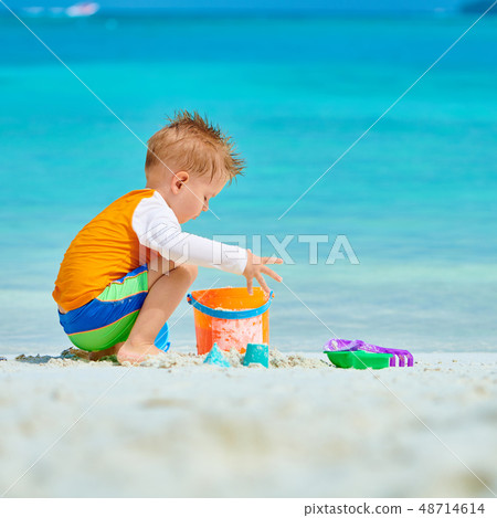 Three year old toddler playing on beach Three year old toddler playing on beach 48714614