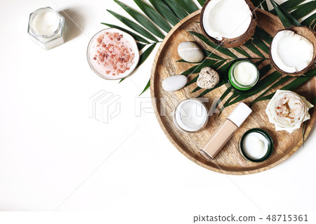 Styled beauty composition. Skin creams, makeup bottle, rose and pebble stones on wooden tray 48715361