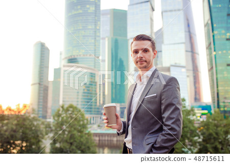 Businessman looking on copy space while standing against glass skyscraper Businessman looking on copy space while standing against glass skyscraper 48715611