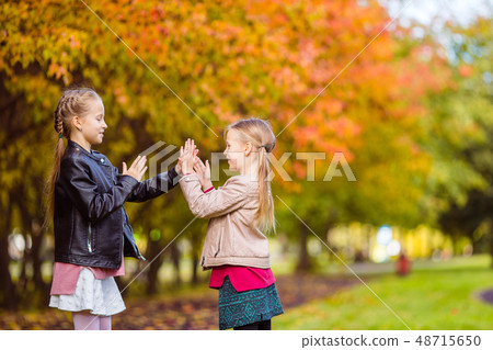Little adorable girls at warm day in autumn park outdoors 48715650