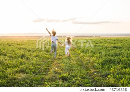 Family, summer and holiday concept - Back view of mother holding her daughter's hand running towards Family, summer and holiday concept - Back view of mother holding her daughter's hand running towards 48716858