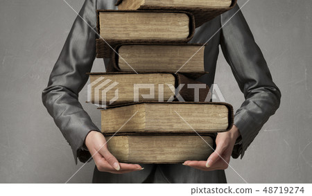 Woman carrying stack of books Woman carrying stack of books 48719274