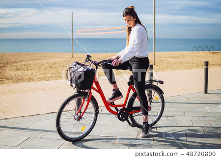 Woman riding bicycle along beach sand at summer time 48720800