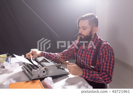 Writer's day and technology concept - Handsome writer surrounded by scraps of paper focused on work Writer's day and technology concept - Handsome writer surrounded by scraps of paper focused on work 48721961