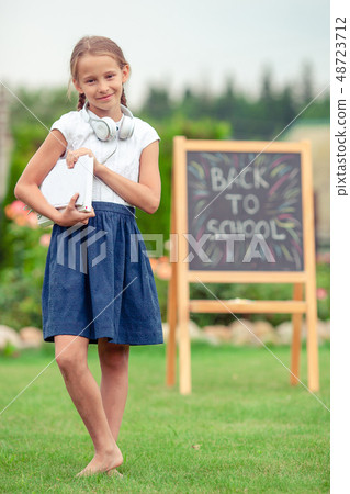 Happy little schoolgirl with a chalkboard outdoor 48723712