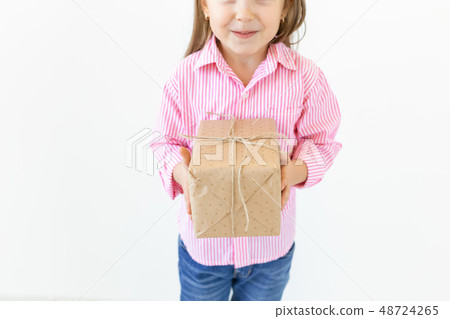 Holiday and presents concept - Close up of little girl smile and holding gift box 48724265