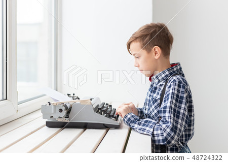 people, children and style concept - young boy with old black typewriter on white background. people, children and style concept - young boy with old black typewriter on white background. 48724322