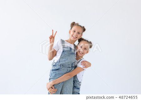 Family and love concept - two smiling twin sisters hugging over white background 48724655