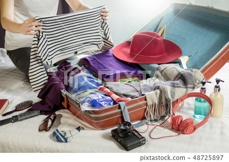 Woman hand packing a luggage for a new journey and Woman hand packing a luggage for a new journey and 48725897