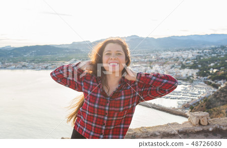 Happiness, emotions and travel concept - Laughing freckles woman with curly hair outdoors Happiness, emotions and travel concept - Laughing freckles woman with curly hair outdoors 48726080