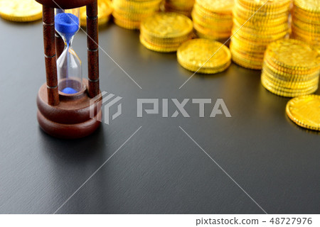 Gold coins and hourglass Gold coins and hourglass 48727976