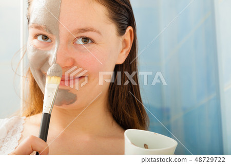 Woman applying mud facial mask Woman applying mud facial mask 48729722