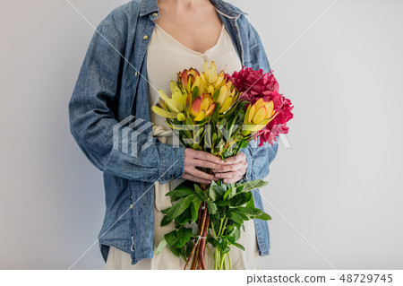 Female hands holding bouquet of peonies and  Leucadendron 48729745
