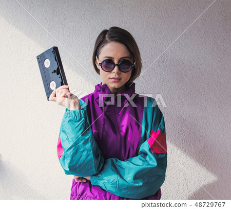 Young woman in 90s style clothes holding VHS cassette Young woman in 90s style clothes holding VHS cassette 48729767