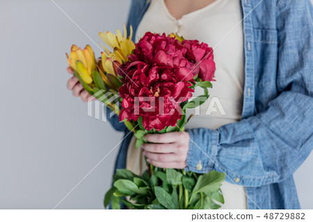 Female hands holding bouquet of peonies and  Leucadendron 48729882