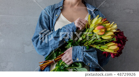 Female hands holding bouquet of peonies and  Leucadendron 48729926