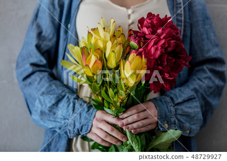 Female hands holding bouquet of peonies and  Leucadendron 48729927