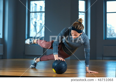 Fit and muscular woman doing intense core workout with kettlebell in gym. Female exercising at 48731068