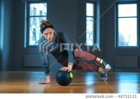 Fit and muscular woman doing intense core workout with kettlebell in gym. Female exercising at Fit and muscular woman doing intense core workout with kettlebell in gym. Female exercising at 48731115