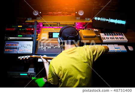 back of musician recording guitar sound in studio 48731400