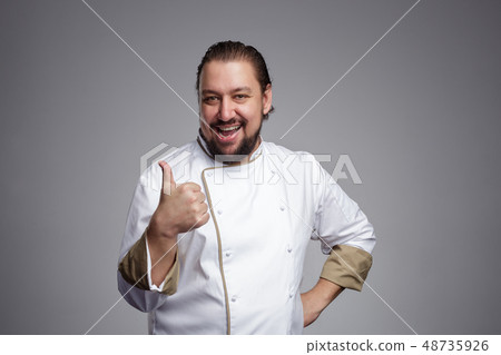 Pleased chef laughs and shows thumbs up. Pleased chef laughs and shows thumbs up. 48735926
