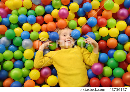 Happy little boy having fun in ball pit with 48736187