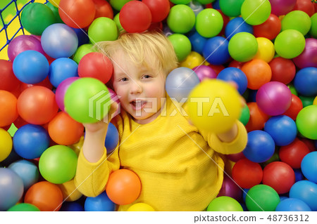 Happy little boy having fun in ball pit with 48736312