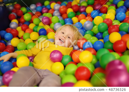 little boy having fun in ball pit with balls little boy having fun in ball pit with balls 48736326